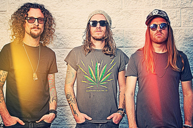 Three band members in t-shirts and sunglasses