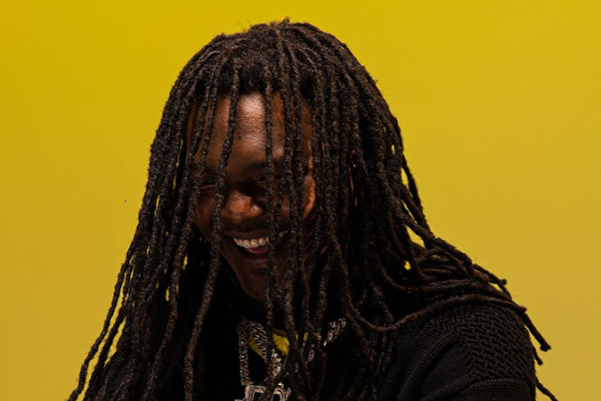 Young Nudy smiling with yellow backgound