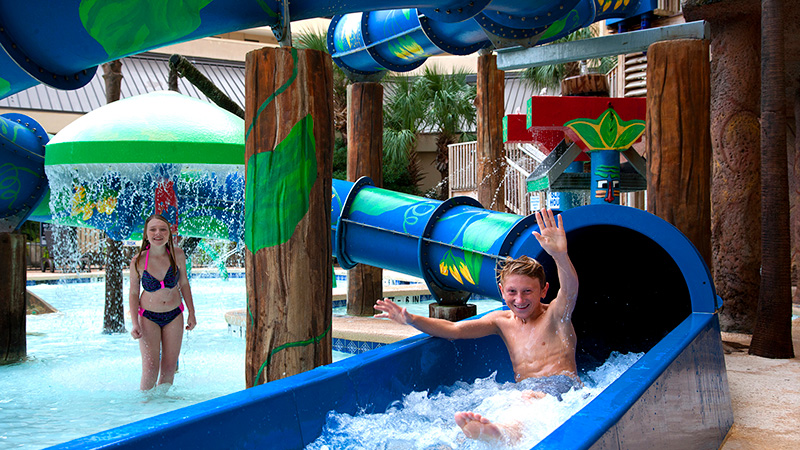 Boy coming down waterslide with girl watching at Ocean Reef Resort