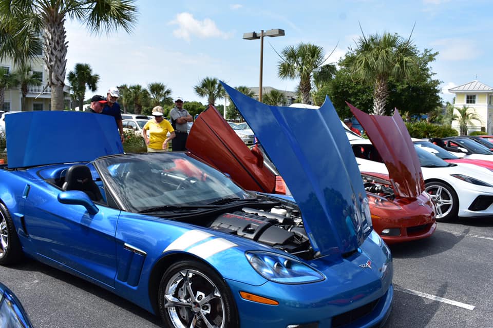 Blue and red corvettes on display with hoods up