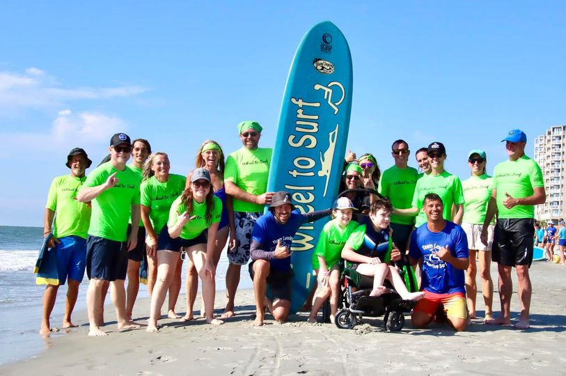 Participants on beach with Wheel to Surf surfboard
