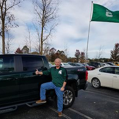 UFB Spartan fan with green truck, green shirt and Spartans flag