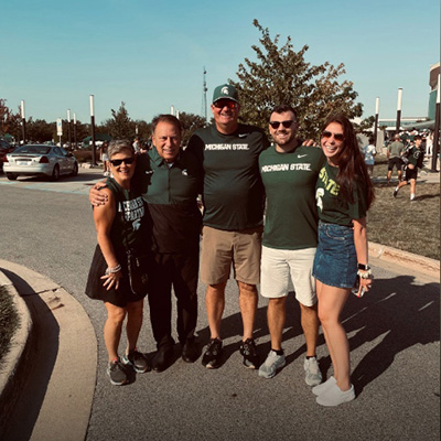 UFB 5 Spartans fans in MSU shirts outside athletic complex