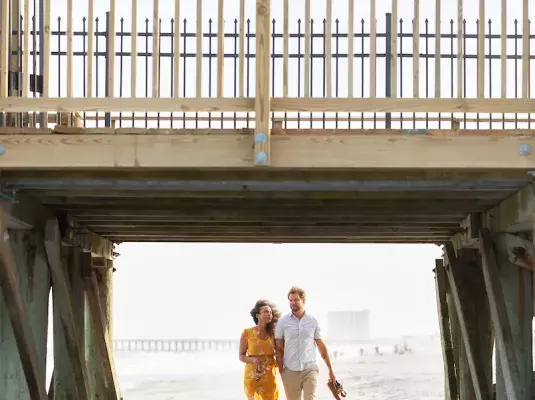 Couple walking under the pier in Myrtle Beach