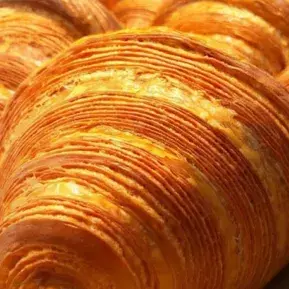 Golden croissants with flaky, layered pastry texture. Freshly baked French pastries ideal for a culinary tourism experience and breakfast indulgence.