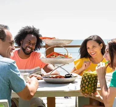 Friends eating and smiling at the beach