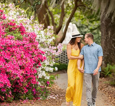 Couple walking in Brookgreen Gardens with flowers