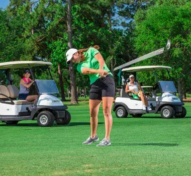 Female golf with golf carts behind her