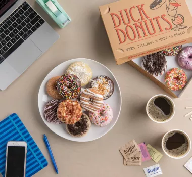 Duck Donuts Duck Donuts in an office setting with laptops and coffee.