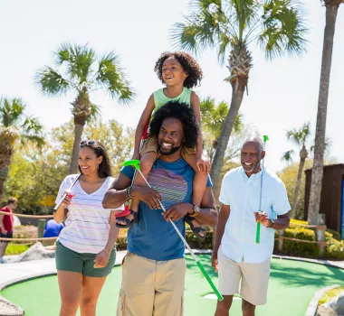 Family playing mini golf - son on dad's shoulders