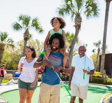 Family playing mini golf - son on dad's shoulders