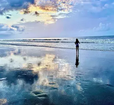 A little girl walks on the beach at sunset