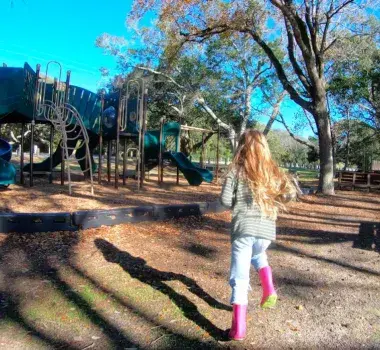 Little girl running toward the playground at the Myrtle Beach State park.