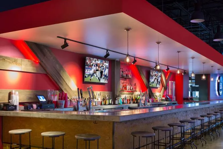Empty bar with bar stools with two TVs behind bar