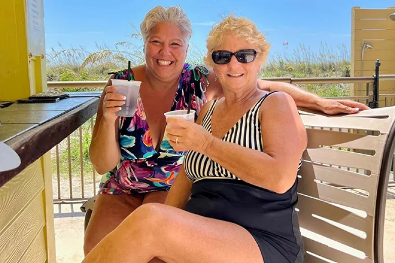 Two ladies smiling enjoying cocktails at outdoor bar