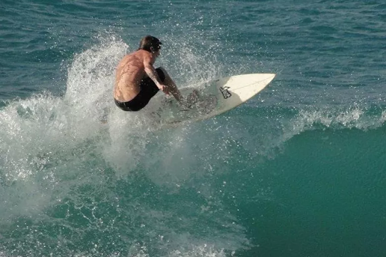 Jack's Surf Lessons surfer on ocean hitting a wave