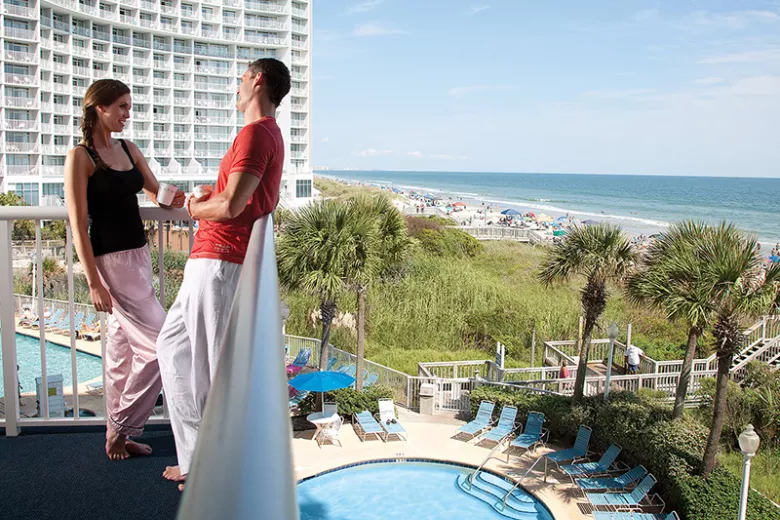 Sea Watch couple on balcony with pool and ocean view