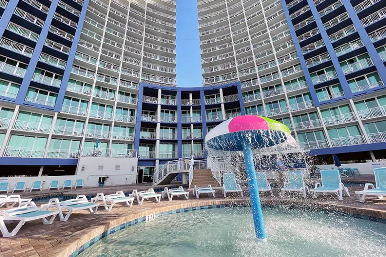 Outdoor pool with umbrella style water feature and exterior view of Avista Resort