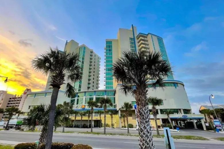 Exterior view of Avista Resort at sunrise with two palm trees in the foreground