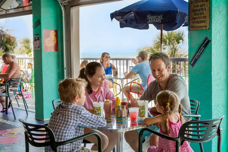 Family at Loco Gecko with pool and beach behind