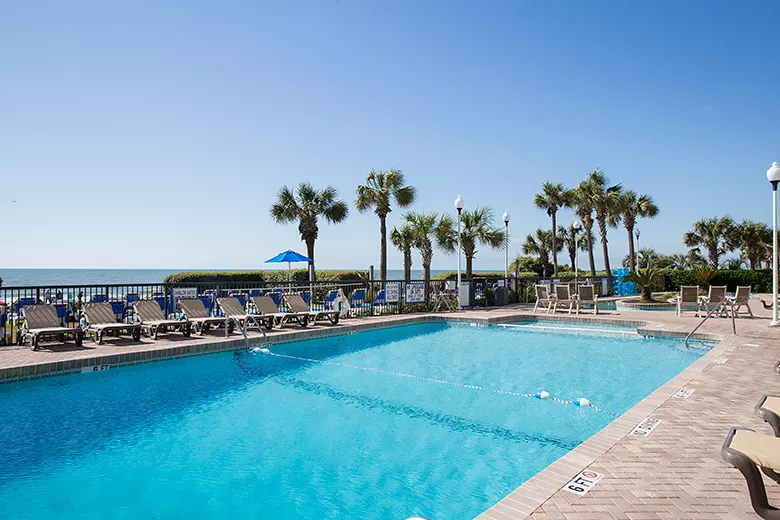 Outdoor swimming pool with palm trees and blue skies