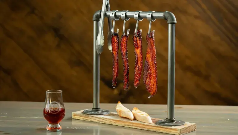 Artisanal charcuterie display with hanging cured meats, crusty bread, and whiskey glass showcasing gourmet food experiences.