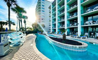 View of an outdoor lazy river and pool deck with blue inner tubes, palm trees and an exterior view of a high rise condominium