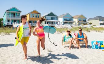 Family on beach with beach home kids running with boogie boards