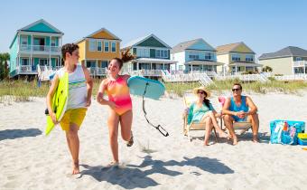 Family on beach with beach home kids running with boogie boards