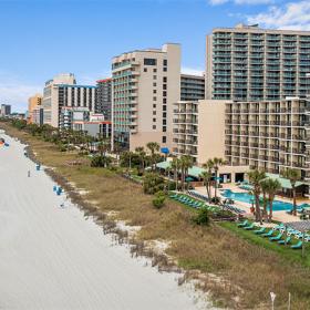 Beachfront with people walking hotels with pools