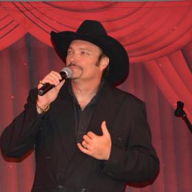 Jeff Gordon in black suit and hat with microphone