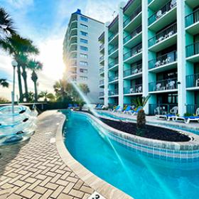 View of an outdoor lazy river and pool deck with blue inner tubes, palm trees and an exterior view of a high rise condominium