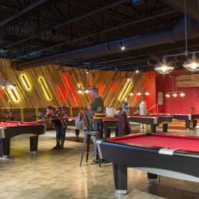 Six pool tables two people playing at two of the tables