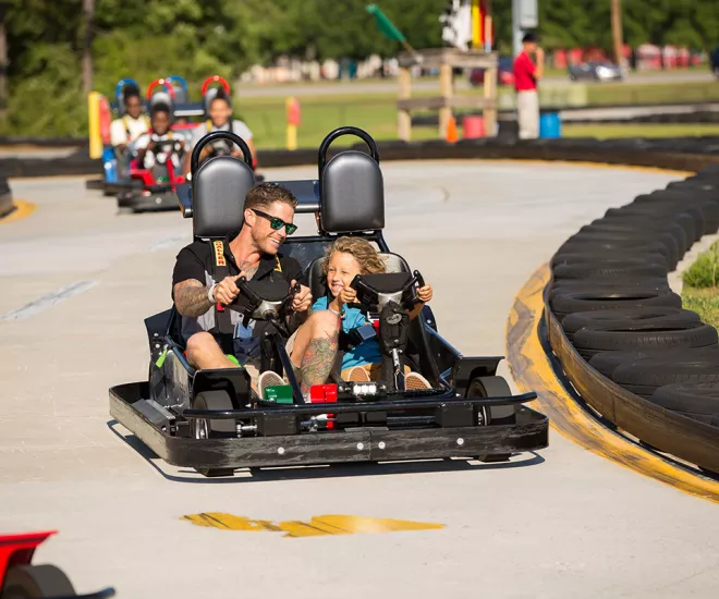 Father and son driving go cart on racetrack