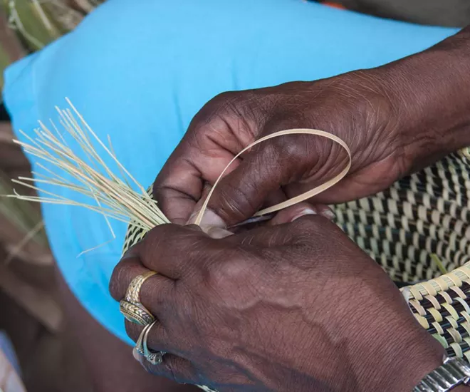 Hands weaving a basket