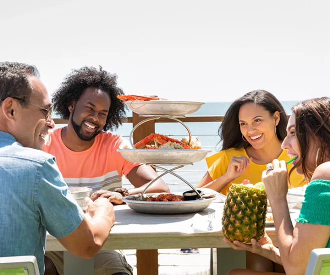 Friends eating and smiling at the beach