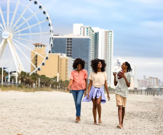 Teens walking with mom on the beach near skywheel