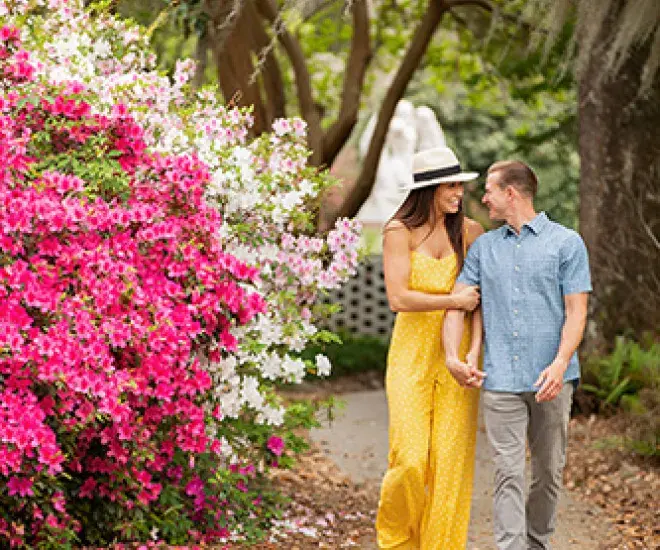 Couple walking in Brookgreen Gardens with flowers