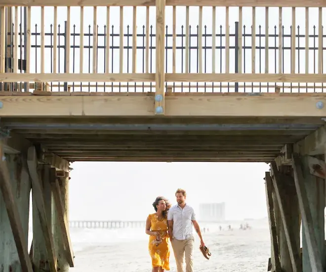 Couple walking under the pier in Myrtle Beach