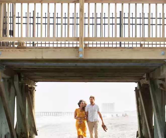 Couple walking under the pier in Myrtle Beach