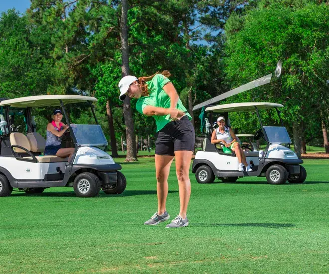 Female golf with golf carts behind her