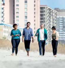 Group of Friends Walking on Beach Near A Hotel