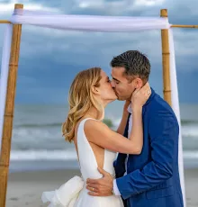 Couple married on the beach kissing