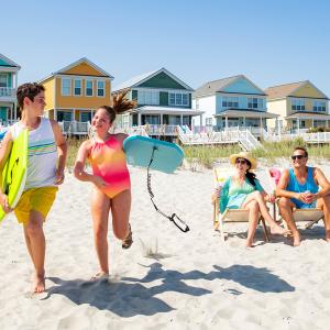 Family on beach with beach home kids running with boogie boards