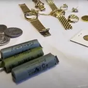 Jewelry, individual and rolled coins displayed on a table