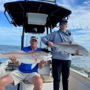 Two men on fishing boat each holding a big fish