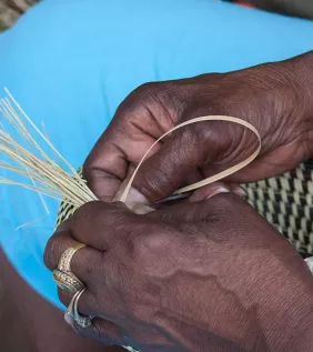 Hands weaving a basket