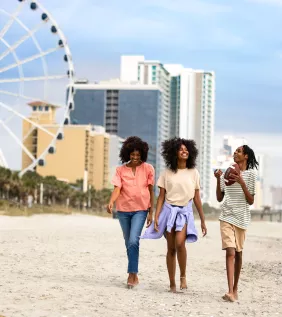 Teens walking with mom on the beach near skywheel
