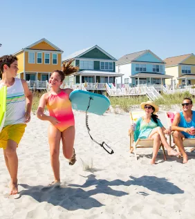 Family on beach with beach home kids running with boogie boards