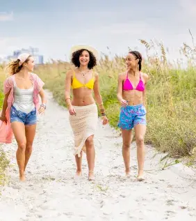 3 friends walking on the beach in between the dunes.